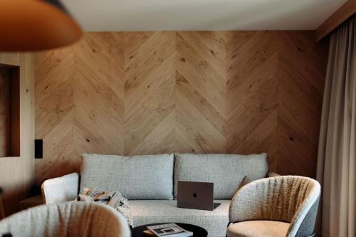 a living room with a couch and a wooden wall at Alpina Alpendorf in Sankt Johann im Pongau