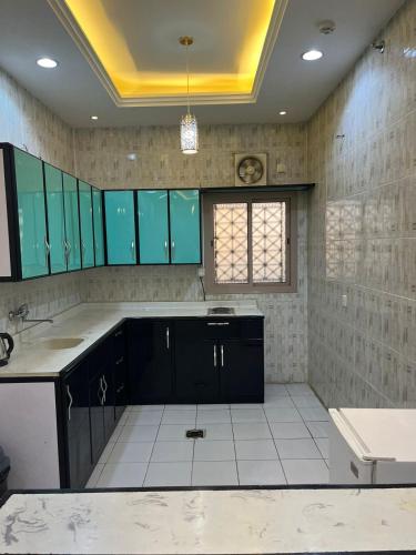 a large kitchen with blue cabinets and white tiles at Rekaz Serviced apartments in Mecca