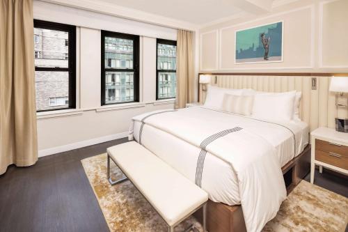 a bedroom with a large white bed and windows at Hilton Club The Quin New York in New York
