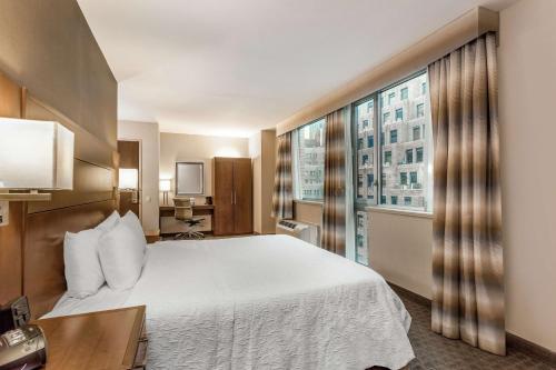 um quarto de hotel com uma cama e uma grande janela em Hampton Inn Manhattan Grand Central em Nova Iorque