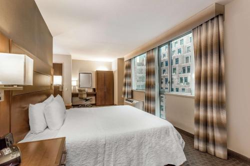 a hotel room with a bed and a large window at Hampton Inn Manhattan Grand Central in New York