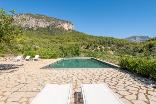 a swimming pool with two chairs and a mountain at Agroturismo Filicumis in Lloseta