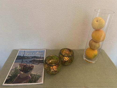 a table with a vase and candles and a magazine at Mysigt boende i Åhus med egen ingång, terass, wifi, tvättmaskin & parkering! in Åhus