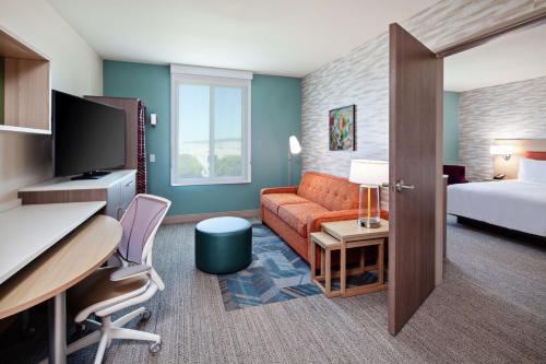 アラメダにあるHome2 Suites By Hilton Alameda Oakland Airportのベッド、ソファ、デスクが備わるホテルルームです。