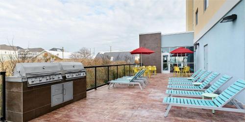 a patio with blue chairs and a grill at Home2 Suites by Hilton Ocean City Bayside in Ocean City