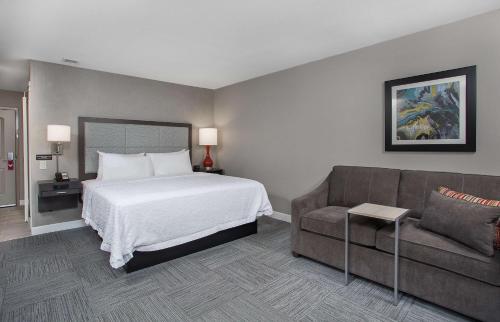 a hotel room with a bed and a couch at Hampton Inn Vincennes in Vincennes
