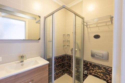 ein Bad mit einer Dusche und einem Waschbecken in der Unterkunft Chic Flat w Balcony 2 min to Beach in Bodrum in Gündoğan