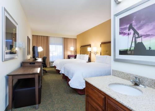 a hotel room with two beds and a sink at Hampton Inn Odessa in Odessa