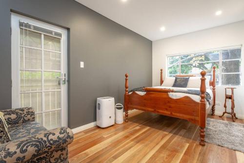 a bedroom with a bed and a chair and a window at Exclusive Art Deco Escape in Tree-lined Kingsford in Sydney