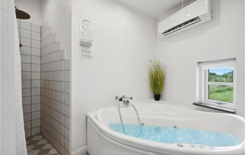KlegodにあるStunning Home In Ringkbing With 4 Bedrooms, Wifi And Indoor Swimming Poolの白いバスルーム(バスタブ付)、窓が備わります。