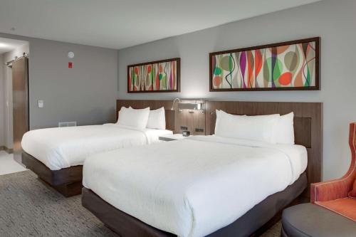a hotel room with two beds and a chair at Hilton Garden Inn Oklahoma City Airport in Oklahoma City