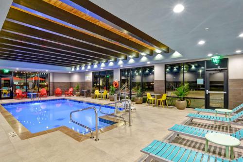 a pool in a hotel with blue chairs and tables at Home2 Suites by Hilton OKC Midwest City Tinker AFB in Midwest City