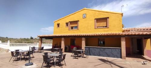 un patio con mesas y sillas frente a un edificio amarillo en Finca Cortés, en Alcaraz