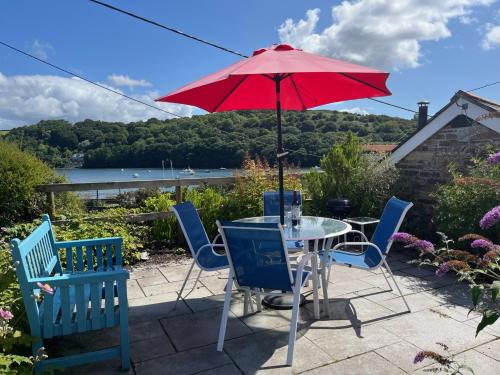 a table and chairs with a red umbrella on a patio at The Boathouse in Golant