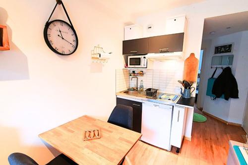 eine Küche mit einem Tisch und einer Uhr an der Wand in der Unterkunft Haven of peace near the beaches in Saint-Malo in Saint-Malo
