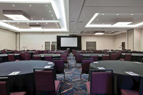 a conference room with tables and chairs and a screen at Embassy Suites By Hilton Oklahoma City Northwest in Oklahoma City