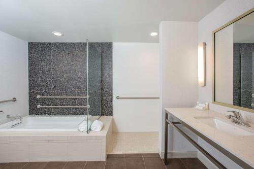 a white bathroom with a tub and a sink at Hilton Garden Inn Olympia, WA in Olympia
