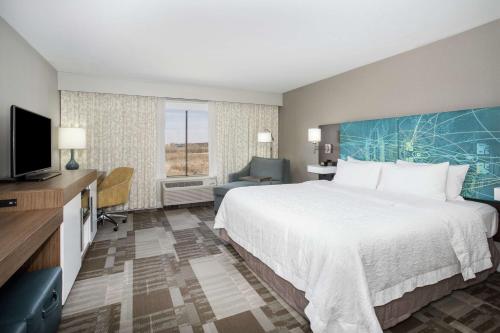ein Hotelzimmer mit einem großen Bett und einem TV in der Unterkunft Hampton Inn Bellevue in Bellevue