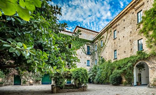 una vista exterior de un gran edificio de ladrillo con árboles en Palazzo Belmonte, en Santa Maria di Castellabate