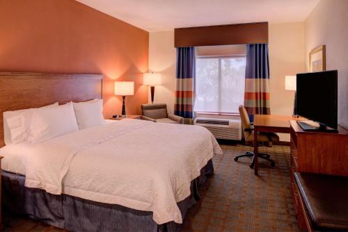 a hotel room with a bed and a desk and a television at Hampton Inn & Suites Ontario in Ontario