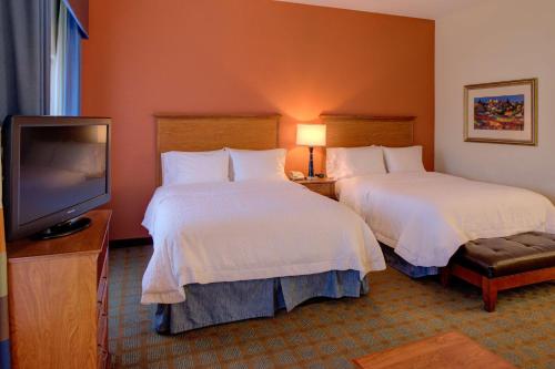 a hotel room with two beds and a flat screen tv at Hampton Inn & Suites Ontario in Ontario