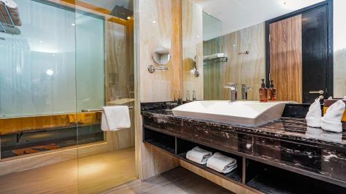a bathroom with a sink and a glass shower at FUGO Hotel Samarinda in Samarinda