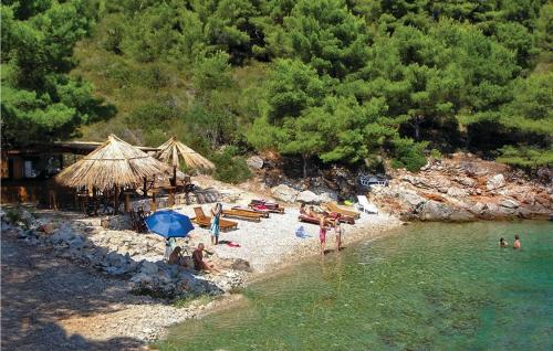 a beach with umbrellas and chairs and people in the water at 2 Bedroom Awesome Home In Stomorska in Stomorska
