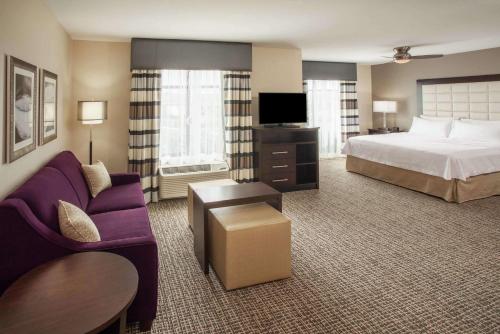 a hotel room with a bed and a purple couch at Homewood Suites by Hilton Munster in Munster