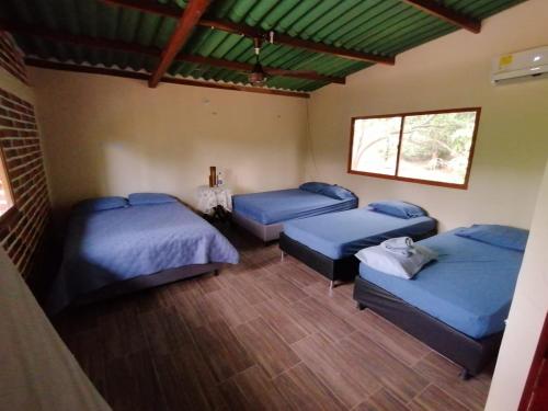 a room with three beds and a window at Cabaña Casa Lila in Santa Marta