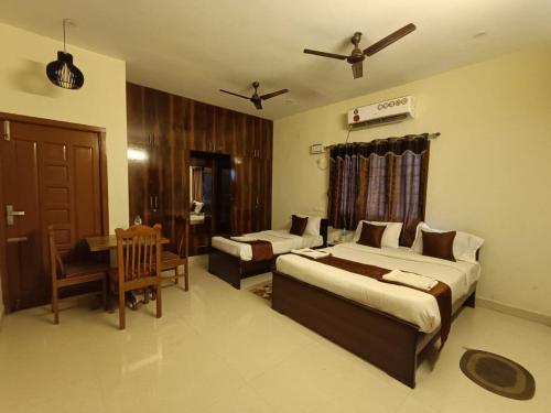 um quarto com 2 camas, uma mesa e uma cadeira em Hotel BlueSky Ramapuram em Chennai
