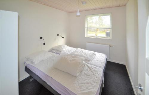 a bedroom with a bed with white sheets and a window at Stunning Home In Glesborg With 4 Bedrooms And Wifi in Fjellerup Strand