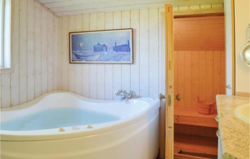 y baño con bañera y una foto en la pared. en Beautiful Home In Vejby With 3 Bedrooms, Sauna And Wifi en Vejby