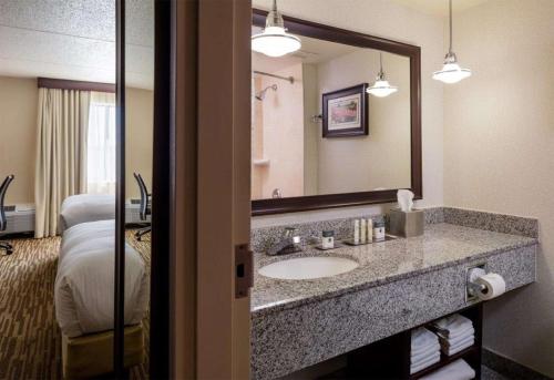 a bathroom with a sink and a mirror and a bed at Doubletree by Hilton, Leominster in Leominster