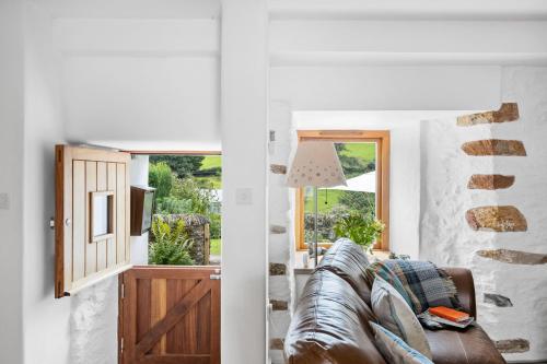 uma sala de estar com um sofá de couro e uma janela em Middle Cottage - Tranquil cottage ideal for walkers em Cornworthy