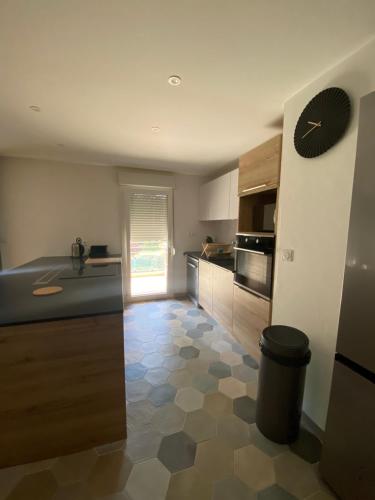 une cuisine avec un comptoir et une horloge au mur dans l'établissement Appartement calme et lumineux proche de Lyon, à Saint-Romain-au-Mont-dʼOr