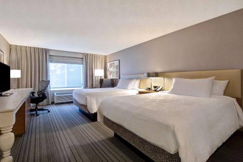 a hotel room with two beds and a desk at Hilton Garden Inn Portland/Beaverton in Beaverton