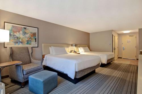 a hotel room with two beds and a chair at Hilton Garden Inn Portland/Beaverton in Beaverton