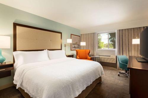 a hotel room with a large bed and chairs at Hampton Inn - Portland/Clackamas in Clackamas