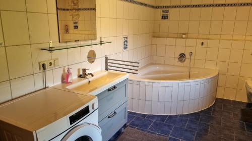 a bathroom with a tub and a sink and a washing machine at Ferienwohnung Bergfreunde in Bergen