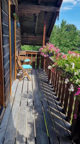 a wooden porch with a bench and flowers at Ferienwohnung Bergfreunde inkl Chiemgaukarte in Bergen