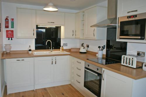 a white kitchen with white cabinets and a sink at Keeper's Lodge in Rowlands Castle