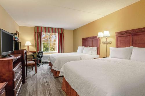 a hotel room with two beds and a flat screen tv at Hampton Inn & Suites Williamsburg Historic District in Williamsburg