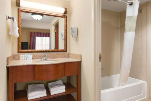 a bathroom with a sink and a tub and a mirror at Hampton Inn & Suites Williamsburg Historic District in Williamsburg