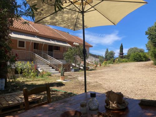 a table with an umbrella in front of a house at Kokkini Peach Budget in Kokkínion