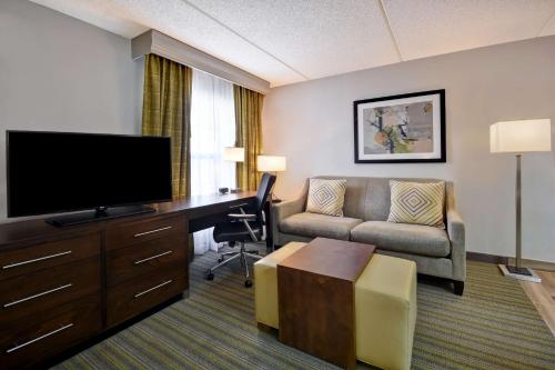 a hotel room with a couch and a desk with a television at Homewood Suites by Hilton Philadelphia-Great Valley in Malvern