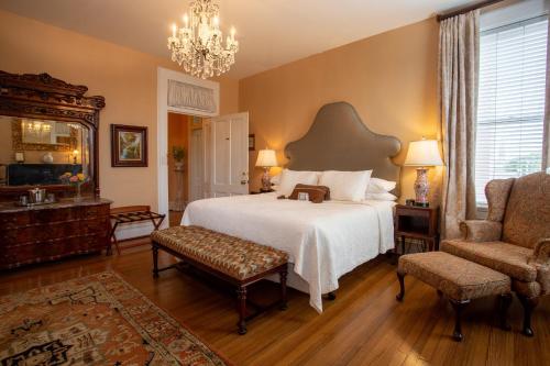 a bedroom with a bed and a chair and a chandelier at Kehoe House, Historic Inns of Savannah Collection in Savannah
