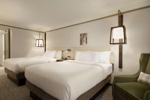 a hotel room with two beds and a chair at Hilton Garden Inn Newtown Square Radnor in Newtown Square