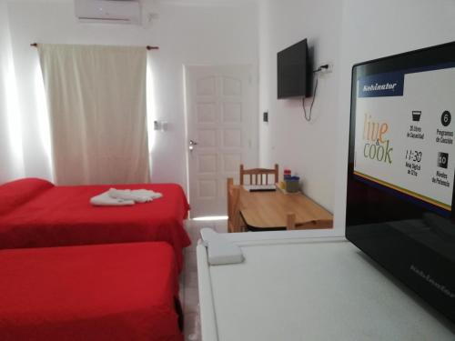 um quarto com uma cama vermelha e uma televisão de ecrã plano em Funcional Centrico em Bahía Blanca