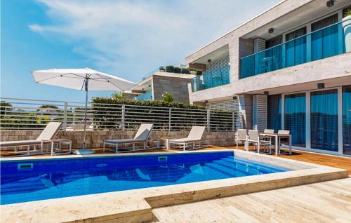 a swimming pool with chairs and an umbrella next to a building at Villa Magnolia in Petrcane