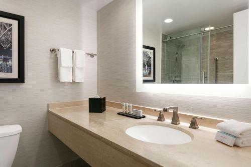 a bathroom with a sink and a toilet and a mirror at Embassy Suites by Hilton Philadelphia Valley Forge in Wayne